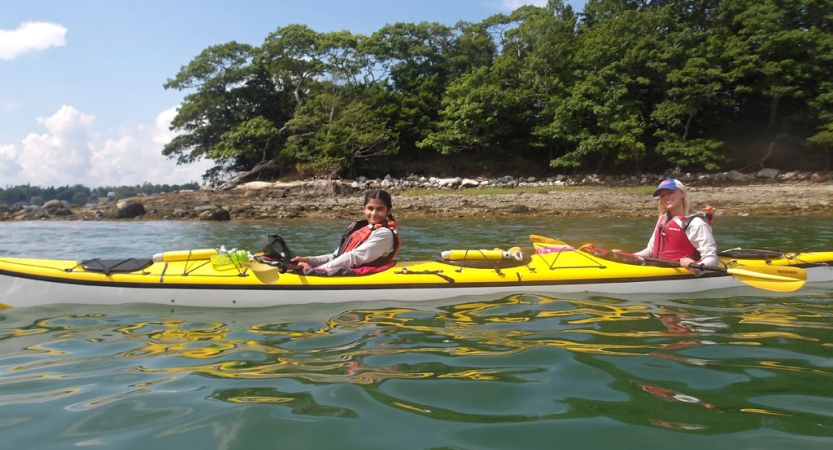 Two people paddle two yellow, individual kayaks